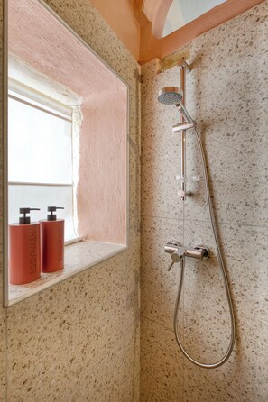 A bathroom with a shower, a window, and two bottles of shampoo on the windowsill. - Cozy 1-bedroom townhome in lovely L-Isla with AC close to Valletta ferry (L-Isla)