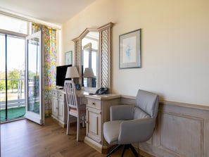 A room with a desk, two chairs, a computer, a telephone, and a framed picture on the wall. - Komfortables Studio am Kurpark in Bad Birnbach (Bad Birnbach)