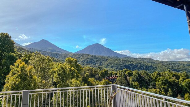 Un balcón con vistas a una cadena montañosa y un bosque frondoso.