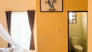 Una habitación con cama, ventana con cortinas, un cuadro en la pared y vistas al baño con inodoro.