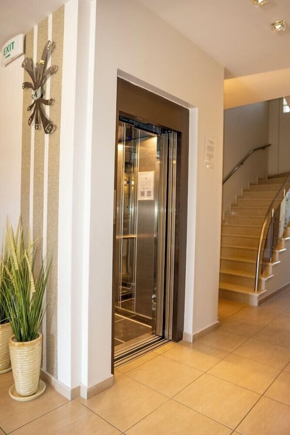Un ascenseur dans le hall d’un hôtel, avec un panneau indiquant la sortie.