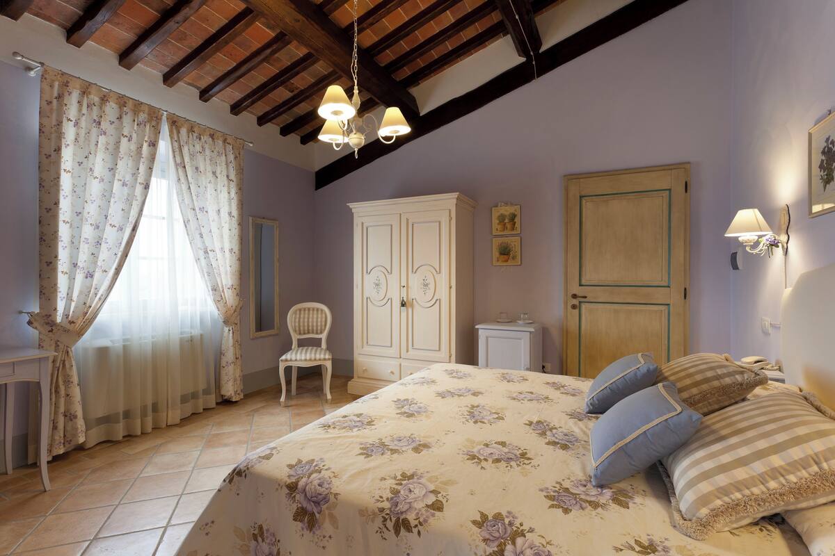 A bedroom with a bed, a chair, a wardrobe, and a desk.