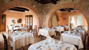 A restaurant with multiple tables set for dining, stone arches, and a rustic interior. - Poggio al Vento Casa Vacanze (Foiano della Chiana)