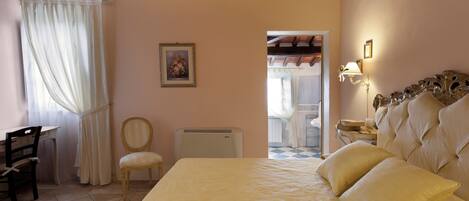 A bedroom with a bed, a desk, a chair, and a radiator.