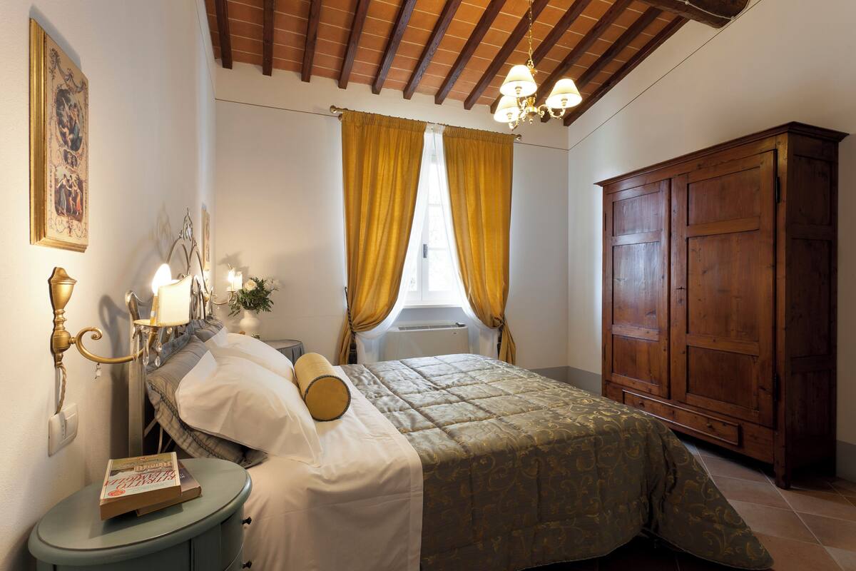 A bedroom with a bed, bedside table, lamp, and wardrobe.