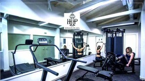 Une salle de sport équipée de tapis de course, d’appareils de musculation et d’un mur recouvert de miroirs.