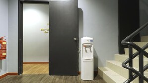 Un pasillo con una puerta cerrada, un dispensador de agua y un extintor.