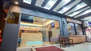 Entrada a una suite de hotel con mostrador de recepción, zona de estar y un diseño de techo moderno.