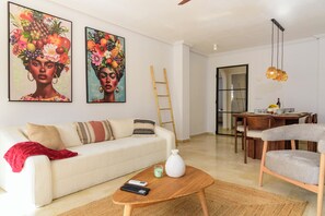 A living room with a sofa, coffee table, and paintings on the wall. - Garden & Patio appartment with swimmingpool (Badia de Xàbia)