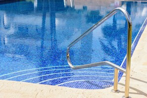 Ein Pool mit Metallgeländer und blauen Mosaikfliesen.