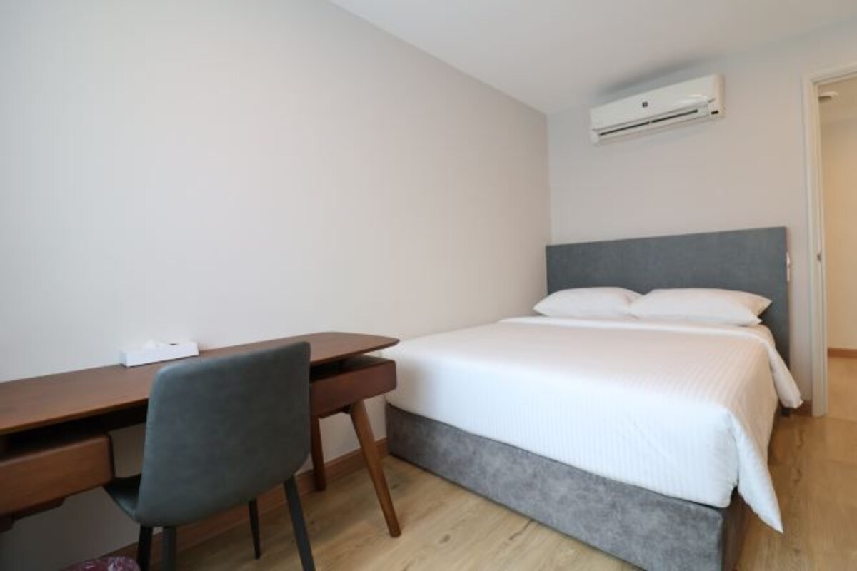 A bedroom with a bed, a desk, and a chair.