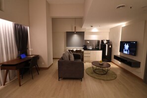Un salon moderne comprenant un canapé, une table basse, un téléviseur et un bureau avec un ordinateur portable.