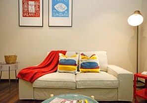 A living room with a sofa, colorful pillows, a red throw blanket, a small side table, and a lamp. - Crown Regency Serviced Suites (Kuala Lumpur)