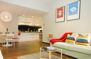 A modern living room with a sofa, a coffee table, and a dining area with chairs and a table. There are two framed artworks on the wall. - Crown Regency Serviced Suites (Kuala Lumpur)