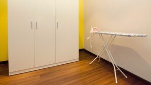 A room with a white wardrobe, a wooden floor, and a white ironing board with an iron. - Crown Regency Serviced Suites (Kuala Lumpur)