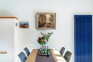 A dining area with a table, chairs, a vase with flowers, and a painting on the wall. - Holiday Home 'Friesenwald' with Private Terrace, Shared Garden, and Wi-Fi (Zetel)