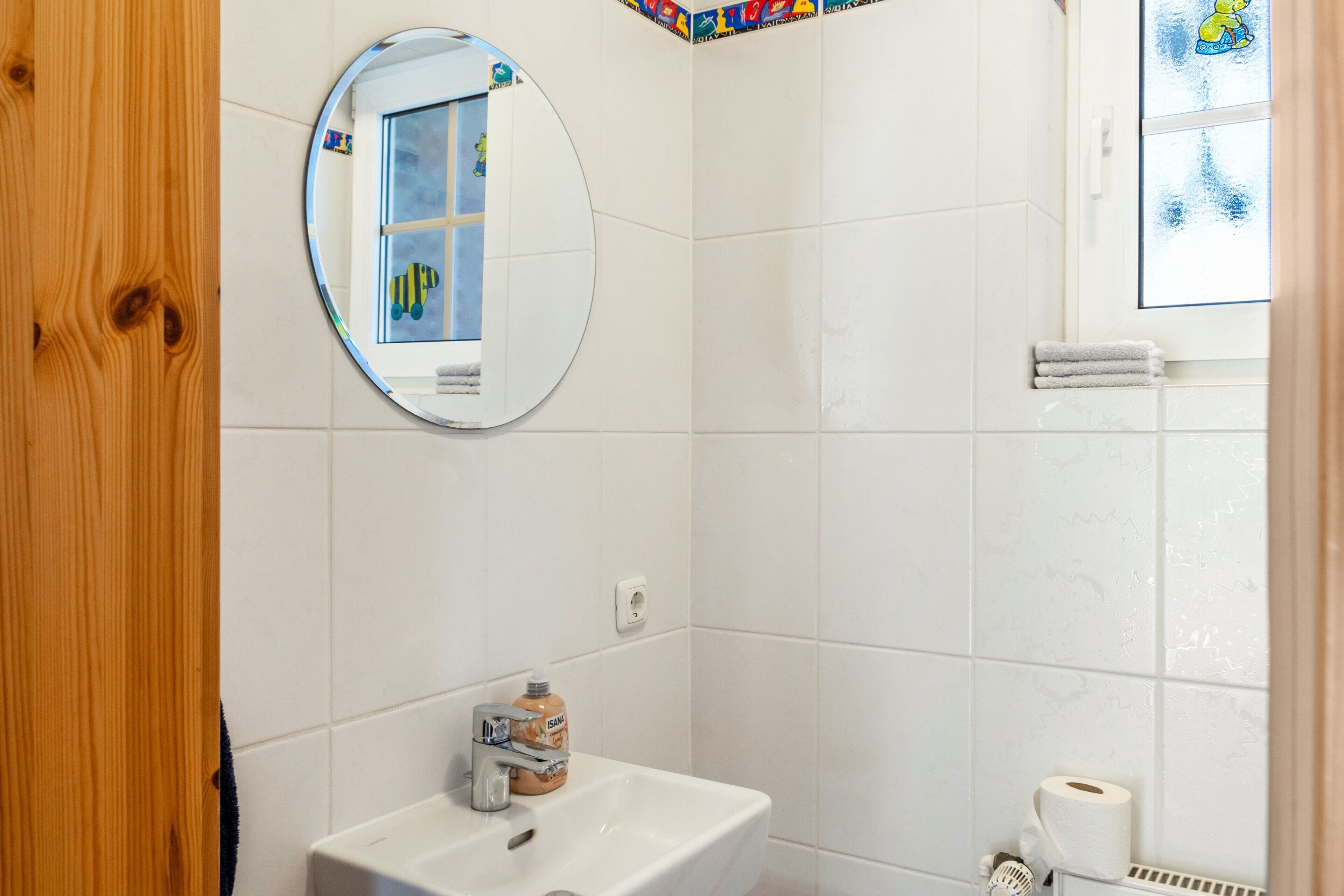 A bathroom with a white sink, a mirror, a window with a view, and a towel rack.