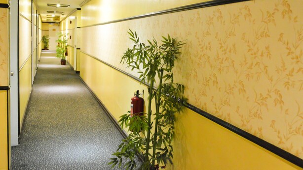 A hallway with yellow walls, a patterned wallpaper, and a fire extinguisher mounted on the wall. - Hotel Sogo Cartimar Recto (Manila)
