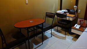 A small hotel room with a single table and two chairs, a mirror, a desk with a telephone, and a small trash bin. - Hotel Sogo Cartimar Recto (Manila)