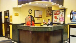 A hotel reception desk with two staff members, a clock, and various framed pictures on the wall. - Hotel Sogo Cartimar Recto (Manila)