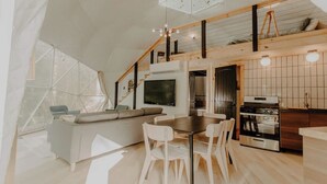 Un interior modern amb zona de menjador, cuina i un espai alt amb llit.