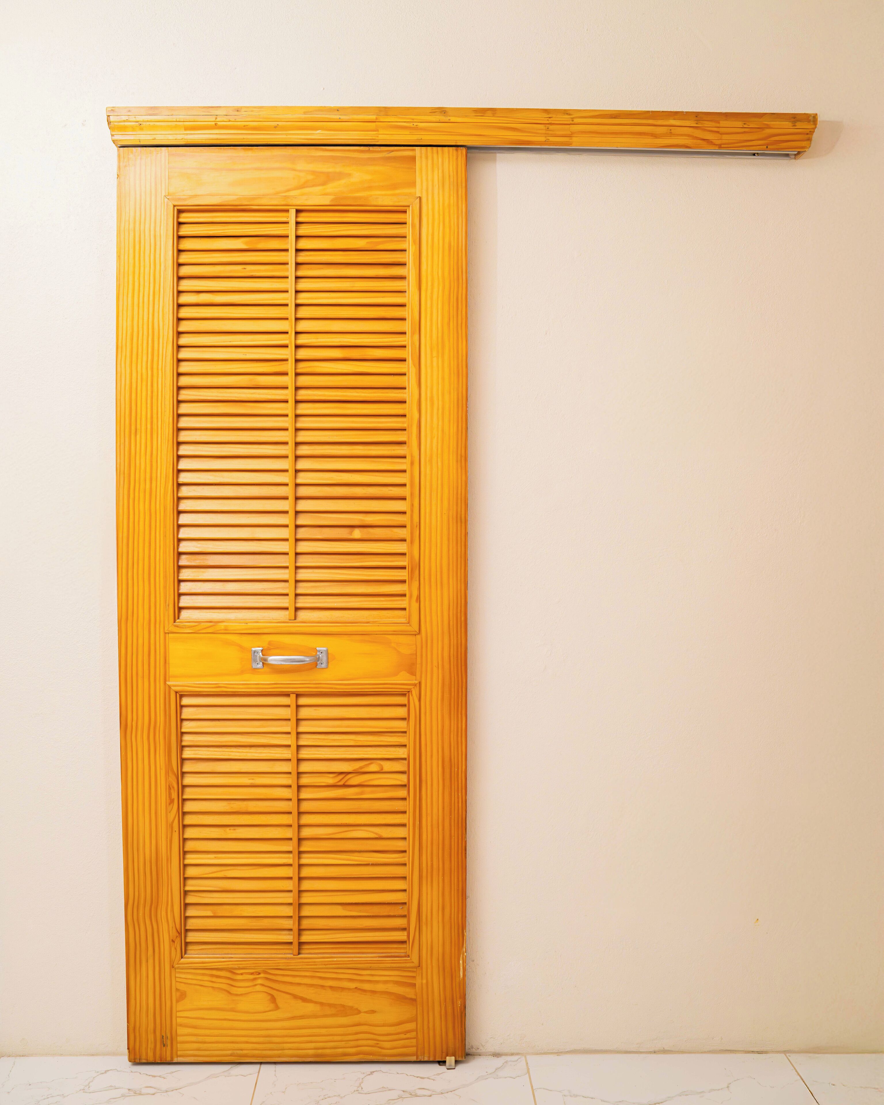 A wooden sliding door with a handle and a small window.