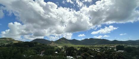 A landscape with mountains, a clear sky, and scattered clouds.