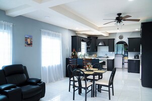 Una cocina moderna con armarios oscuros, una zona de comedor con mesa y sillas, y un ventilador de techo.