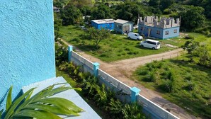 A view from a balcony with a clear sky, a distant castle-like building, and a green landscape. - Chenko Villas & Cars (Jennings)