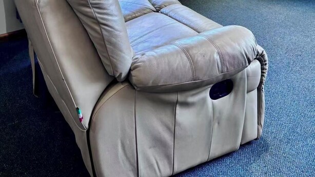Una habitación con una silla reclinable, televisión y ventana con cortinas.