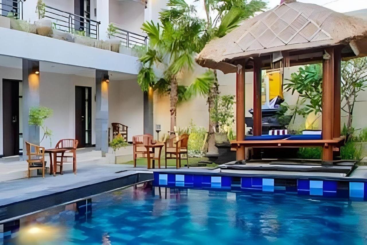 A pool area with a thatched gazebo, lounge chairs, and a small table.