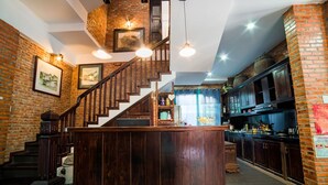 A spacious kitchen with a central island, a brick wall, and a staircase leading to an upper level. - Golden Peach Villa Hoi An (Hoi An)