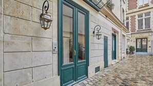 Una estrecha calle adoquinada con un edificio que tiene una puerta verde y un farol en la pared.