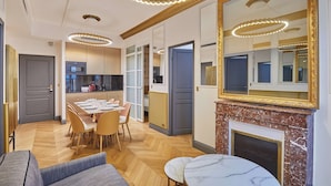 Una sala de estar moderna con chimenea, un comedor con mesa y sillas, y una cocina al fondo.