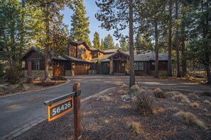 A log cabin with a stone foundation, surrounded by tall pine trees. - Caldera Escape with Access to Exclusive Golf (Sunriver)