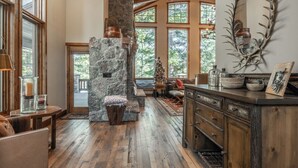 Ein rustikales Interieur mit Kamin aus Stein, Holzbalken und Blick ins Freie.