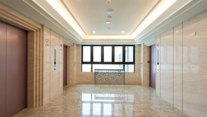 A spacious, well-lit hallway with a polished marble floor, large windows, and modern elevator doors. - Best Hotel (Hualien City)