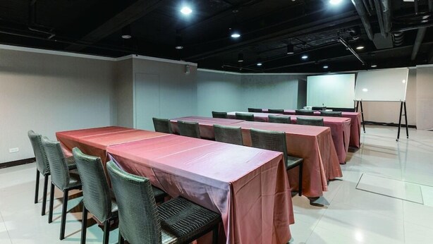 A conference room with multiple tables and chairs, a projector screen, and a whiteboard. - Mola Mola Four Seasons Hotel (Hualien City)