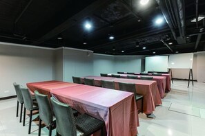 A conference room with multiple tables and chairs, a projector screen, and a whiteboard. - Mola Mola Four Seasons Hotel (Hualien City)
