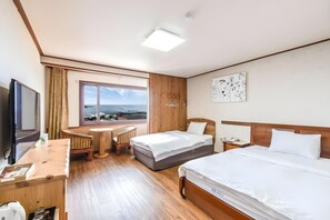 Habitación de hotel con cama, escritorio, silla, televisor y ventana con vistas.