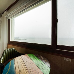 A room with a large window, a round table, and a green chair. - Huesik Hotel Sydney (Jeju City)