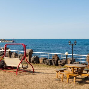 A coastal park with a swing set, picnic tables, and a lamp post. - Huesik Hotel Sydney (Jeju City)