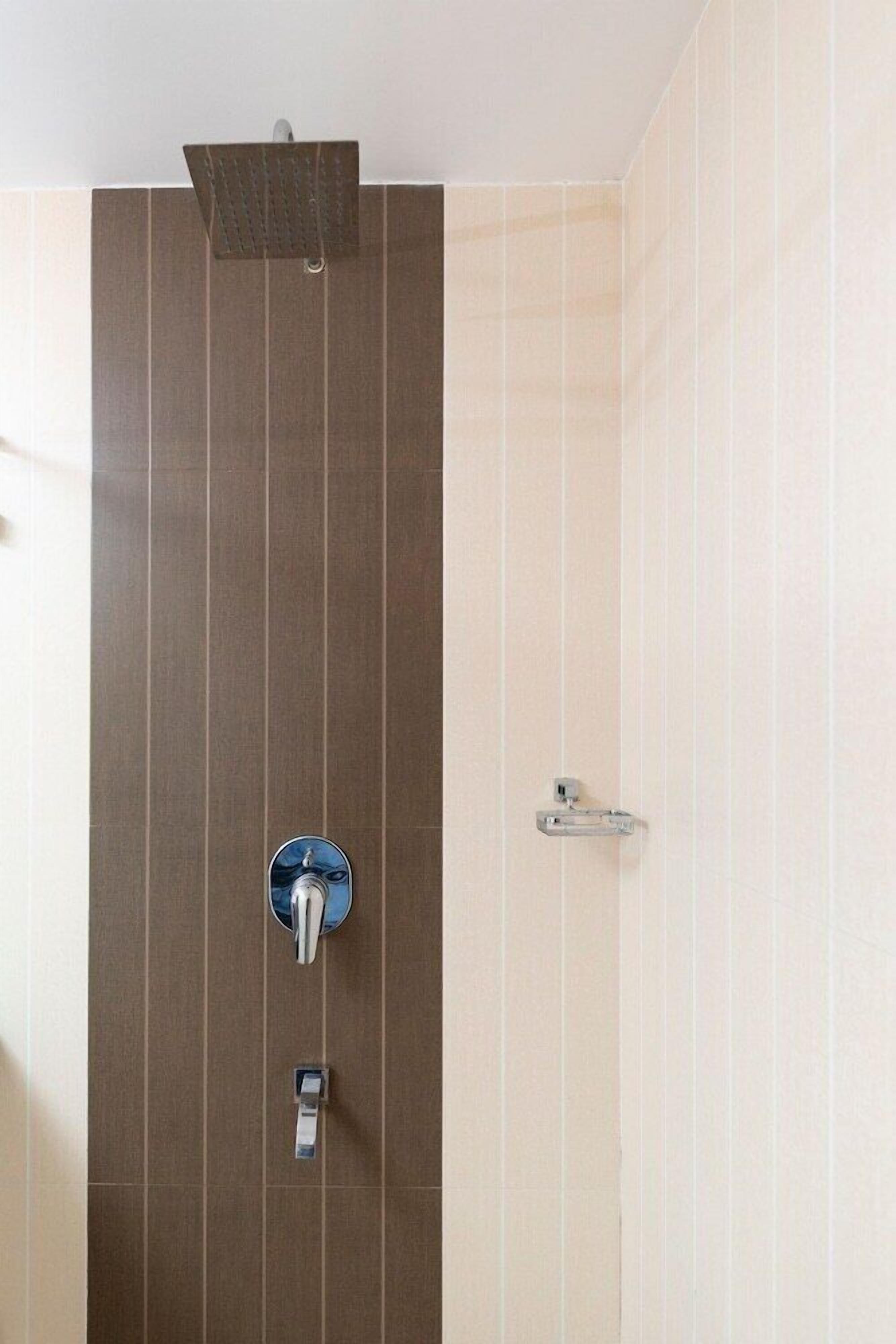 A bathroom with a vertical panel design, a showerhead, and a faucet.
