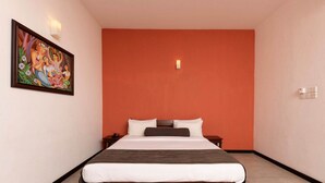 Un dormitorio con una cama, una mesita de noche, una lámpara de pared y un cuadro.