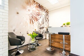 A modern bar area with black leather chairs, a glass table with a vase of yellow flowers, and a wooden counter. - Exclusive Apartments - Atelier Residence (Warsaw)