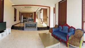 A living room with a sofa, a coffee table, a TV, and a fireplace.
