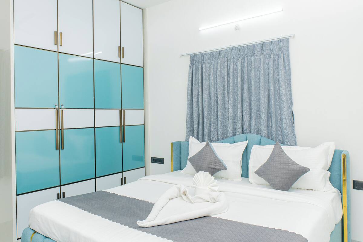 Ein Schlafzimmer mit einem Bett, einem Deckenventilator, einem Kleiderschrank und einem Fenster mit Vorhängen.