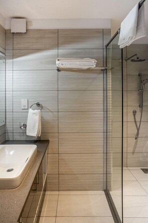 A modern bathroom with a glass shower enclosure, a white sink, and a towel rack. - Yaya Towers and Hotel (Nairobi)