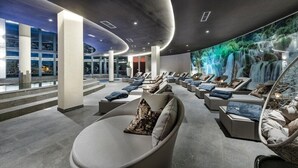 Un espace spa moderne doté de fauteuils inclinables et d’une fresque représentant une cascade.