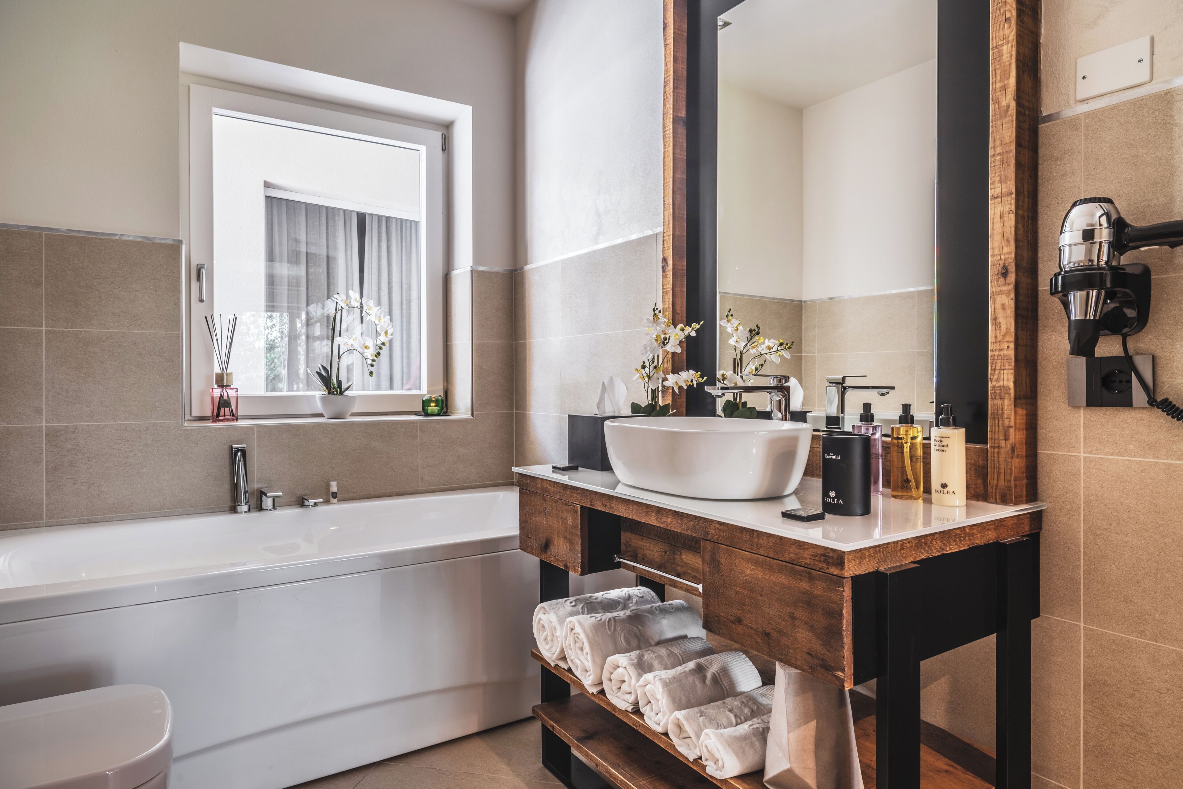 A modern bathroom with a freestanding bathtub, a large mirror, and a wooden vanity with a white sink.